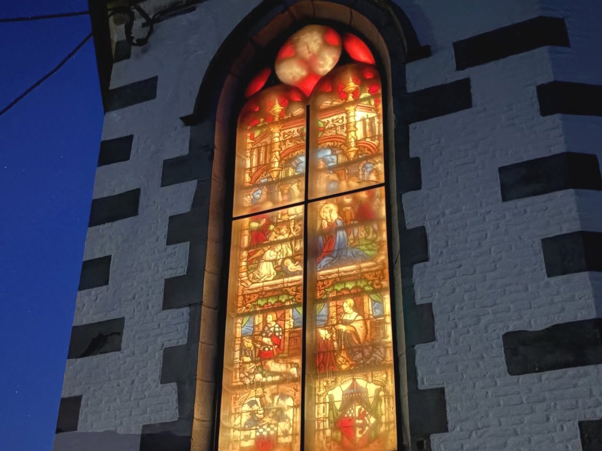 Gros plan sur un vitrail de l'église d'Oisquercq, éclairé de l'intérieur.